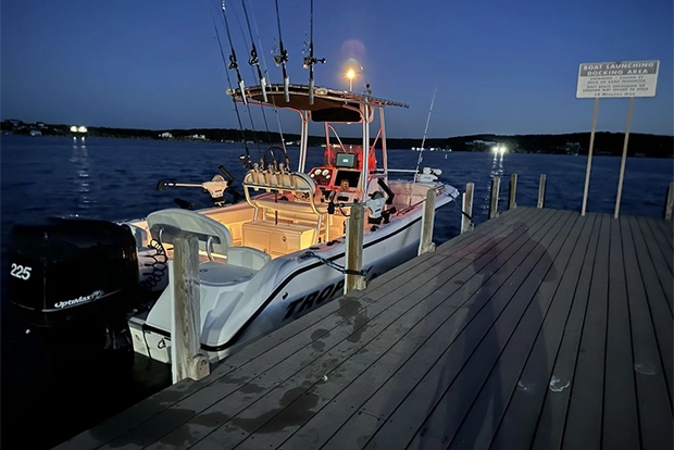 Fishing Boat Docked at Lake with Multiple Rods and Gear